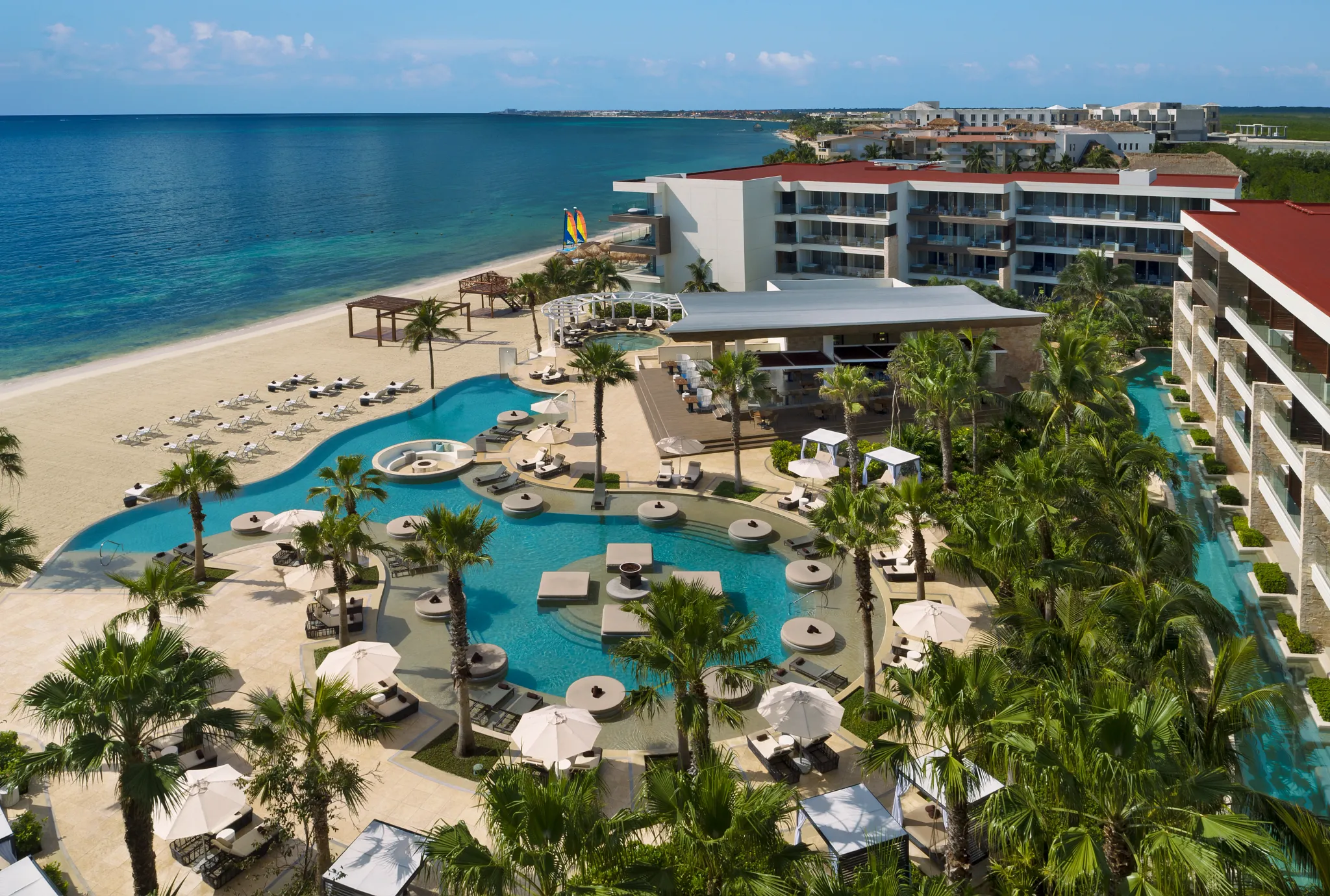 Aerial view of the infinity pool and beachfront at Secrets Riviera Cancun Resort & Spa overlooking the turquoise Caribbean Sea.