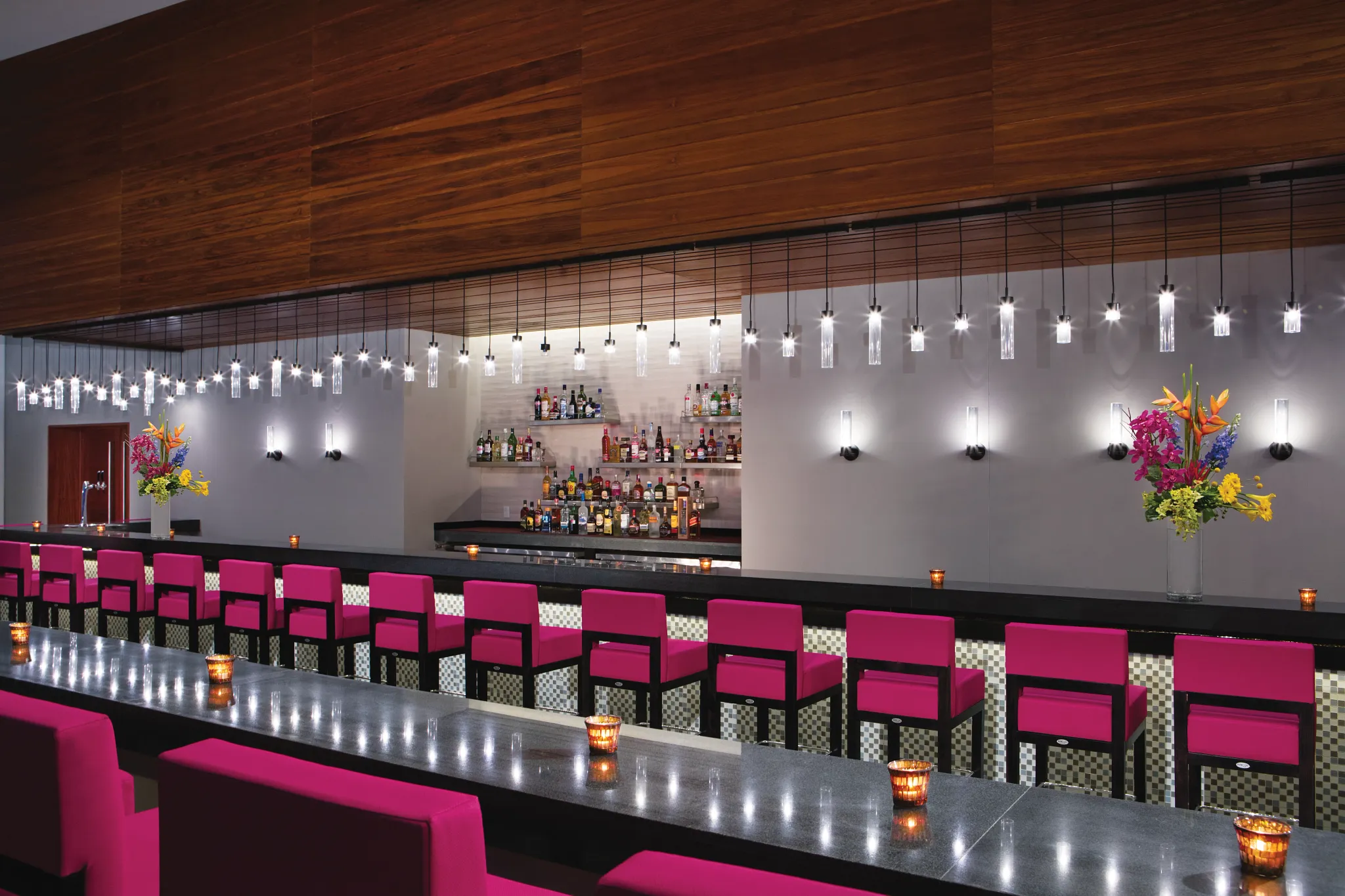 Showstopper Theater Bar at Secrets Riviera Cancun featuring vibrant pink bar stools, modern lighting, and premium cocktails during live entertainment.